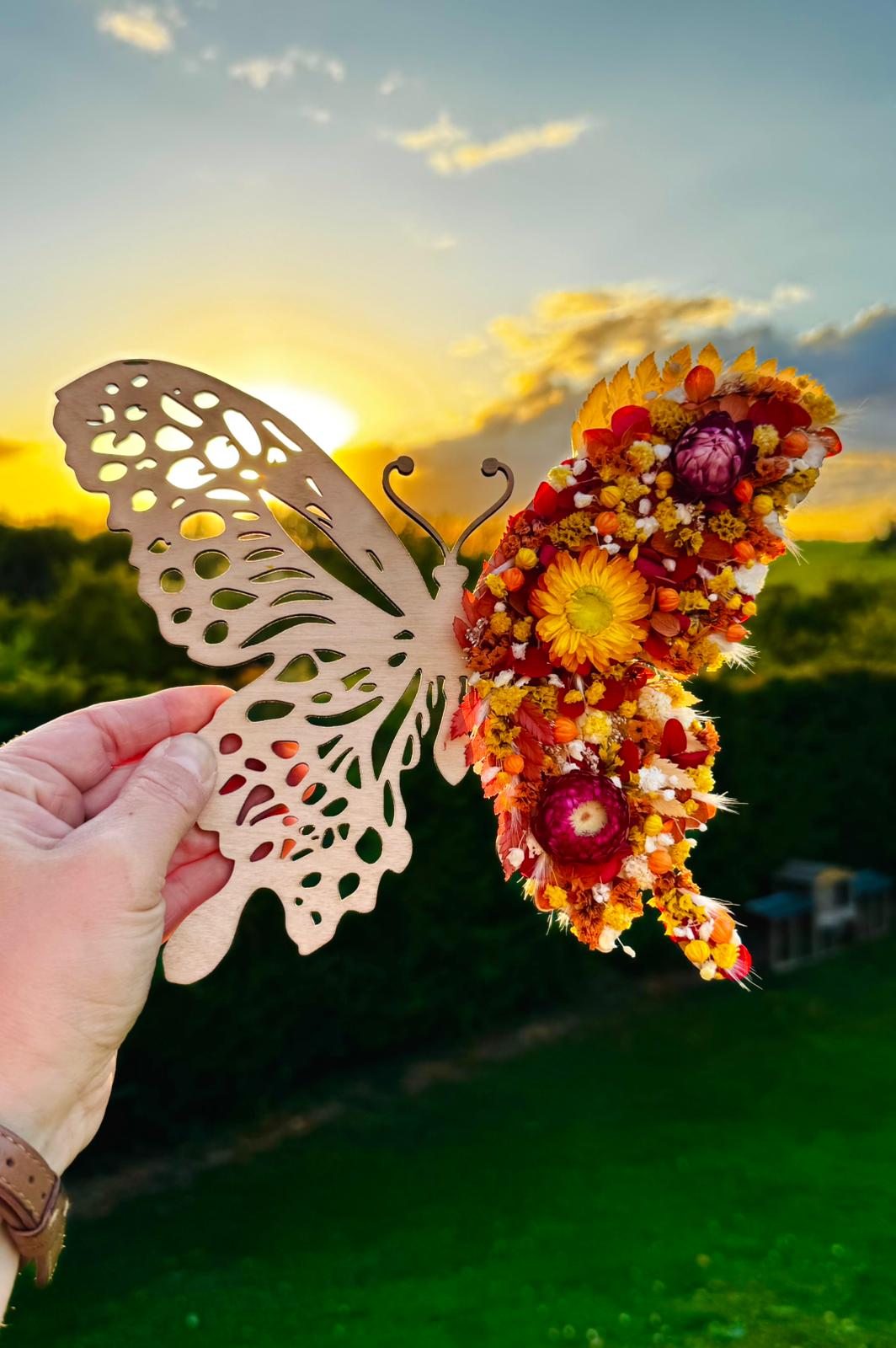 Papillon en bois unique de L'atelier Bcréa, avec une aile sculptée et une aile recouverte de fleurs séchées aux teintes chaudes.