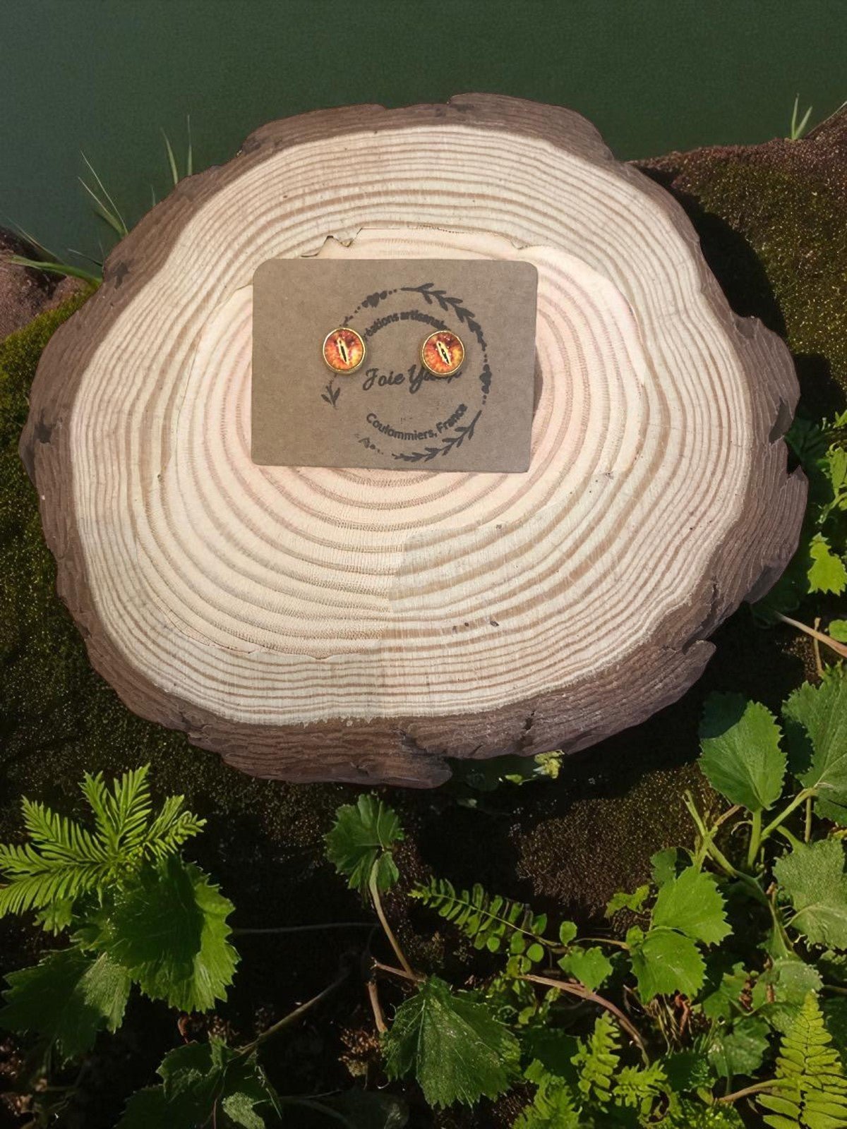 Découvrez les boucles d'oreilles œil de dragon signées Jessica Deelyah, un bijou artisanal unique en acier inoxydable et argile polymère, décoré de feuilles d'or scintillantes et marbrées.