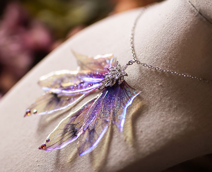Détail des Ailes holographiques du collier Source aux Fées, montrant l'effet arc-en-ciel sous la lumière, fabriqué avec des matériaux non toxiques.