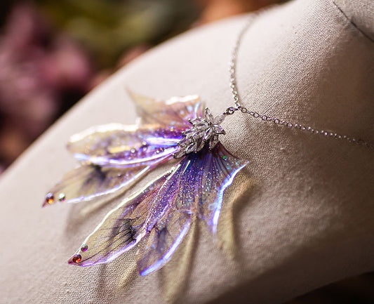 Détail des Ailes holographiques du collier Source aux Fées, montrant l'effet arc-en-ciel sous la lumière, fabriqué avec des matériaux non toxiques.