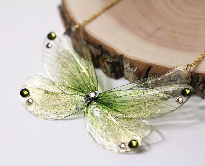 Collier Danse des Druides, composé de huit Ailes de Fées vert Tilleul et paillettes irisées, avec un Cristal transparent et des strass Swarovski, fait à la main en laiton plaqué or 18 carats.