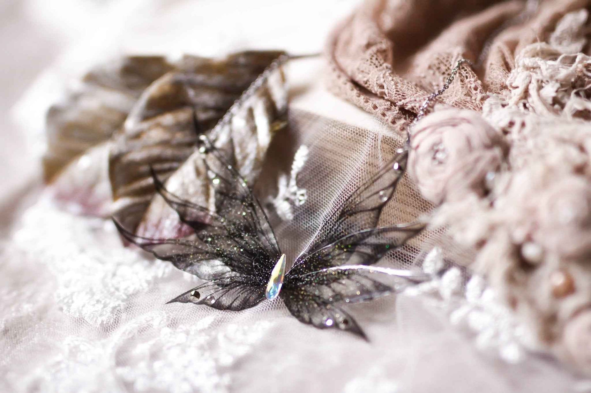 Collier Cendre de Morrighan de Faërie avec des ailes de fées en dégradé noir, ornées de paillettes brillantes et d'un cristal Swarovski, parfait pour une touche féérique.