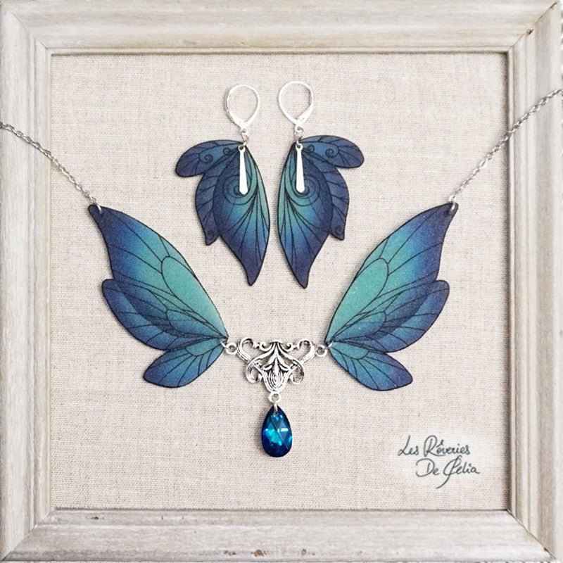 Collier Majestiel et boucles d'oreilles ailes de fée bleu, élégant bijou artisanal de Les Rêveries de Célia, scintillant avec des cristaux Swarovski et des nuances de bleu dégradé.