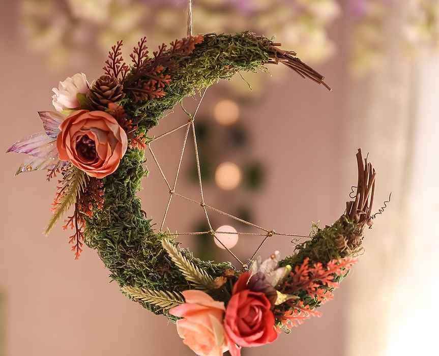 Dentelle de Fée, magnifique décoration en croissant de lune suspendu par Faërie, alliant branchages naturels, mousse, et fleurs artificielles, créant une ambiance enchantée dans votre intérieur.