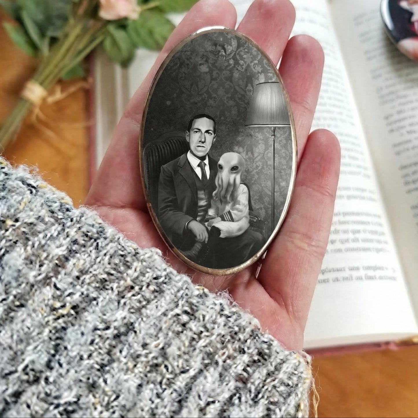 Badge illustré - L'Enfant de l'Abîme - H.P. Lovecraft et l'Héritage de Cthulhu, mettant en scène un homme en costume ancien avec une créature tentaculaire dans une atmosphère lovecraftienne sombre.