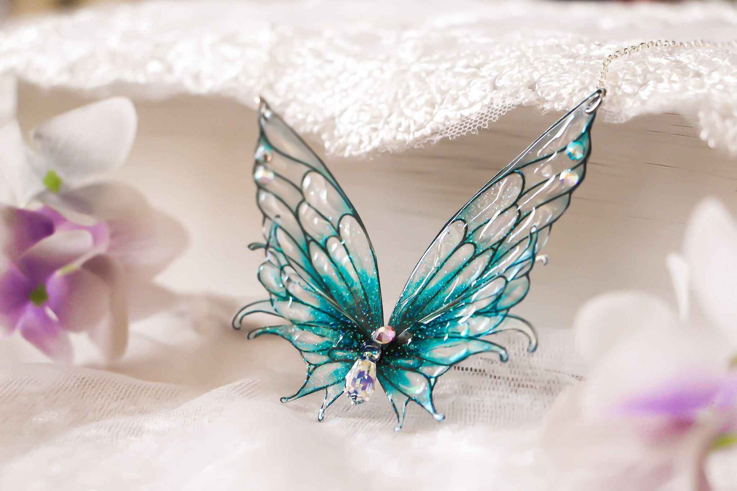 Collier féerique Flots Chantants de Faërie, mettant en avant des ailes de fée turquoise ornées de cristaux Swarovski, capturant l'essence magique de l'océan.