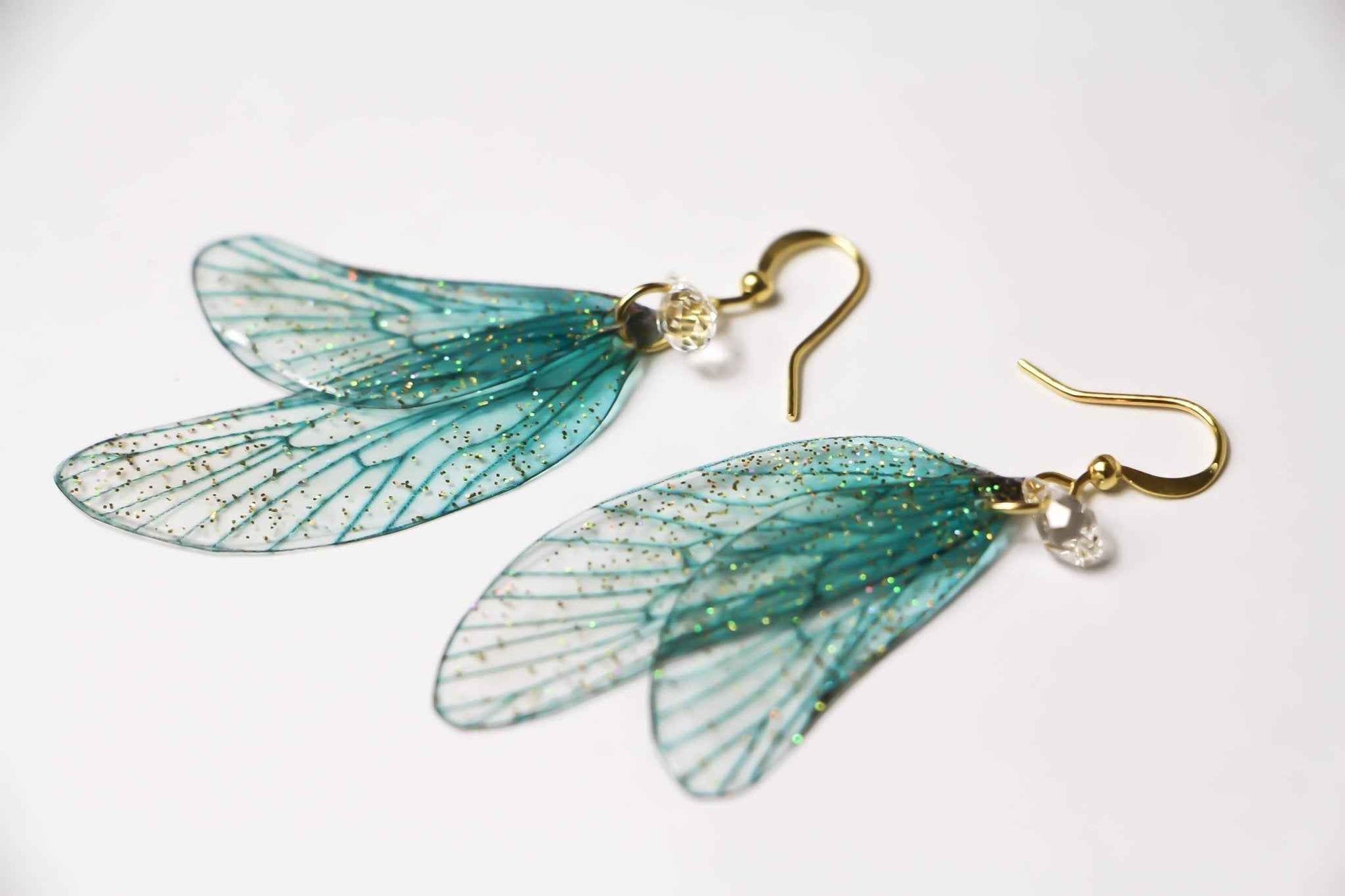 Boucles d’oreilles Fontaine d’Or de Faërie, ornées d’Ailes de Fée turquoise et d’un Cristal Swarovski, captivant l’attention avec éclat et élégance.