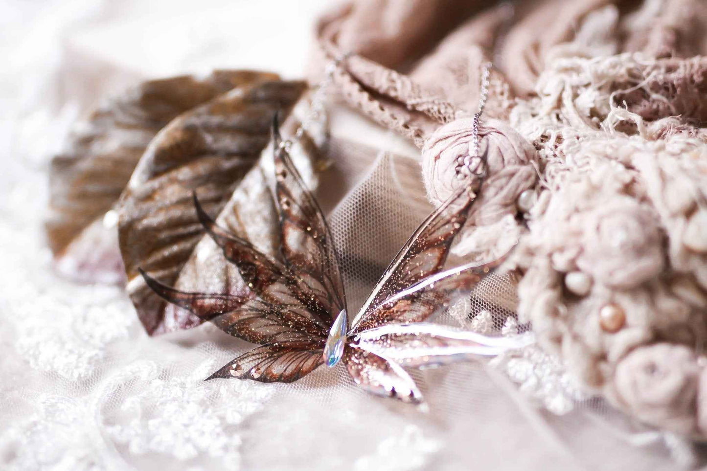 Collier Forêt du Satyre de Faërie, mettant en valeur des ailes de fées en résine marron chocolat avec paillettes irisées, suspendues à une chaîne en acier chirurgical inoxydable.