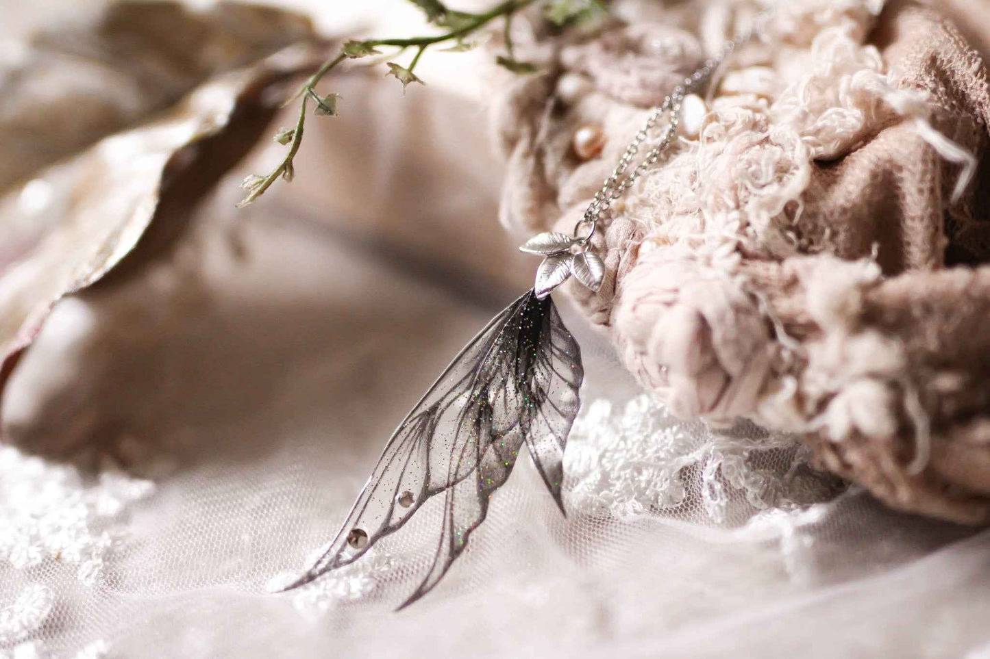 Collier Larme Spectrale de Faërie, un bijou rassembleur de magie avec des ailes de fées noires scintillantes.