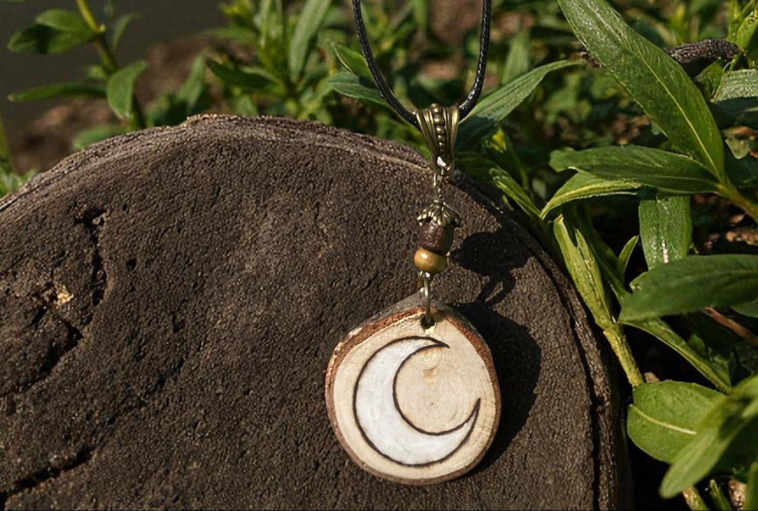 Pendentif Lune de Faërie, un bijou en bois naturel évoquant les mystères de la nuit, avec un design unique gravé à la main.
