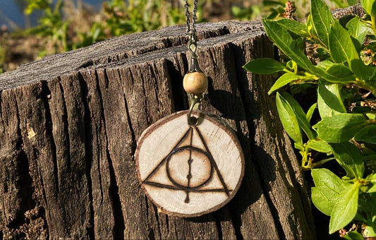 Pendentif Reliques de la Mort de Faërie, un bijou artisanal en bois naturel avec pyrogravure unique, symbolisant la magie et l'artisanat traditionnel.