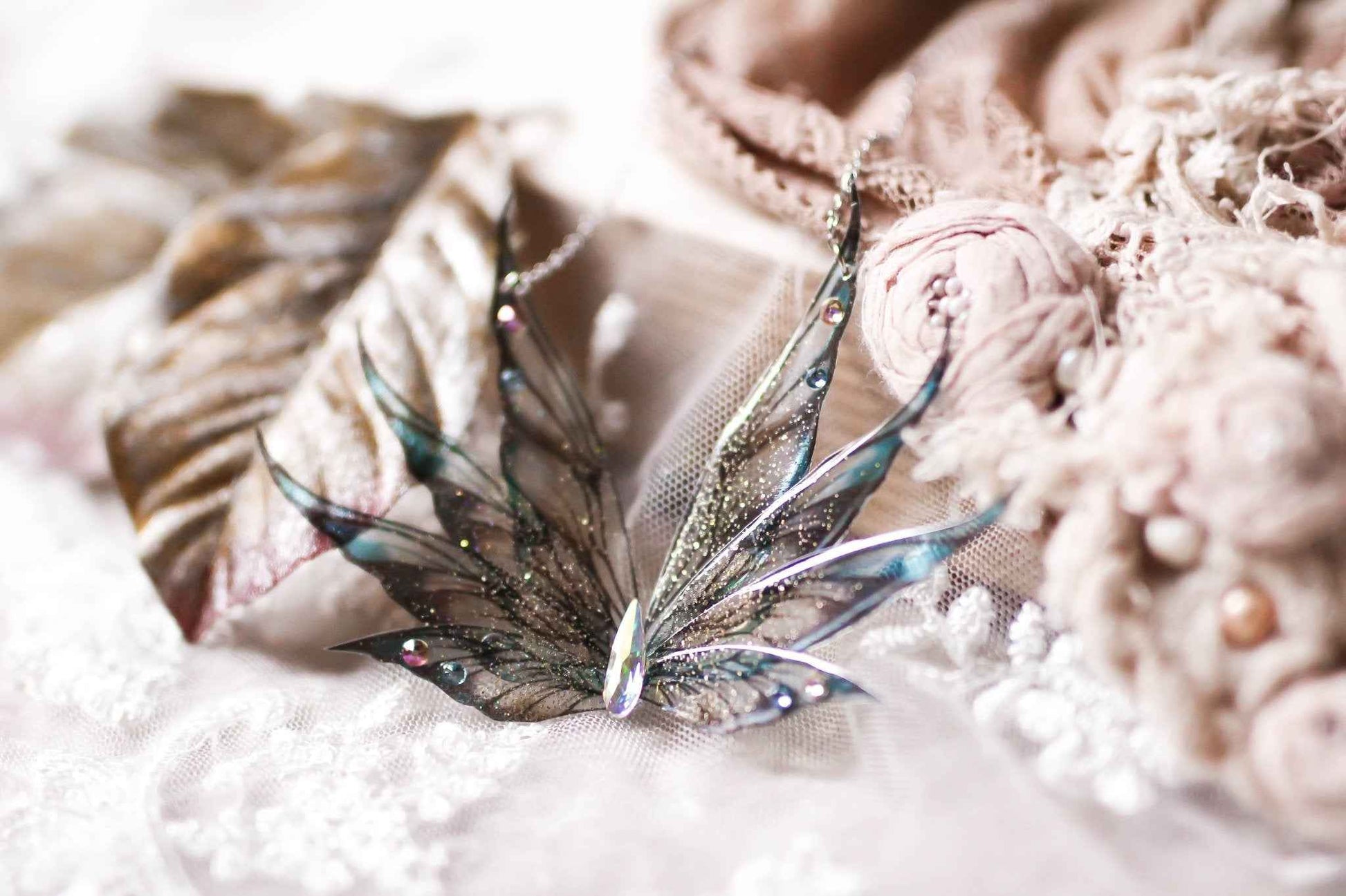 Collier magique Sirène Ailée de la marque Faërie, mettant en valeur ses Huit Ailes de Fées scintillantes dans un dégradé bleu et doré, avec une navette en cristal Swarovski au centre, conçu en acier chirurgical inoxydable.