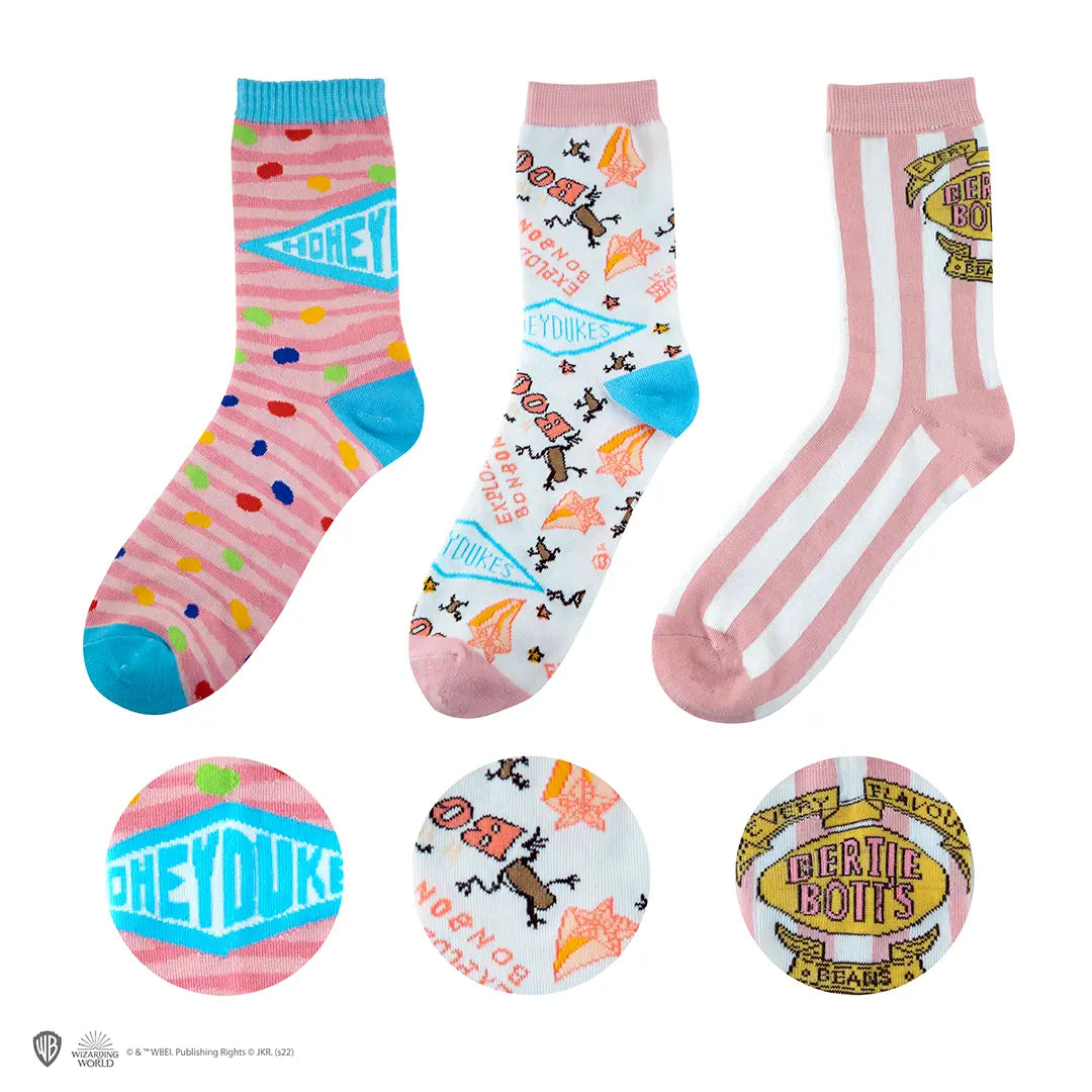 Lot de 3 Paires de Chaussettes Honeydukes - Harry Potter, montrant des motifs colorés inspirés de la confiserie magique.