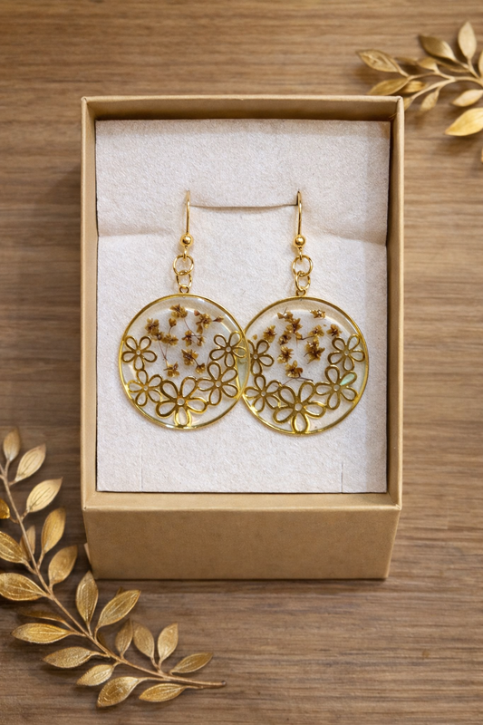 Boucles d’Oreilles Couronne Florale Dorée en résine transparente et fleurs naturelles, un bijou artisanal élégant qui évoque la poésie végétale.