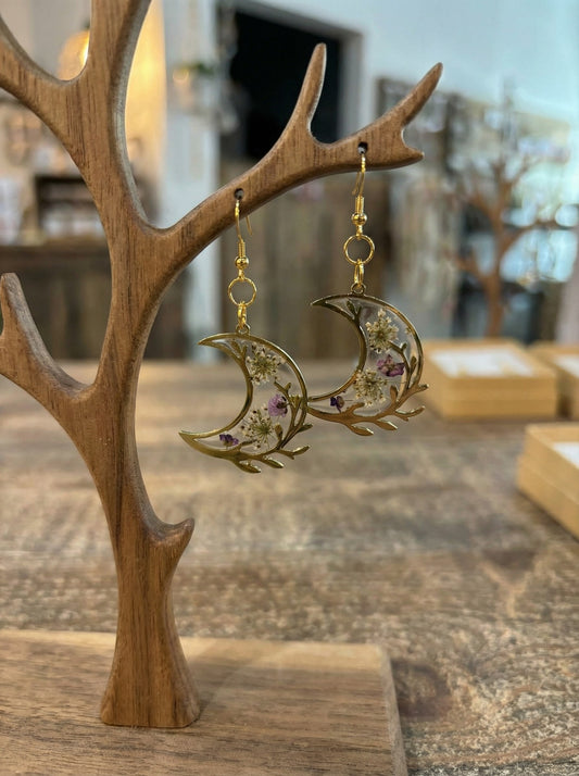 Boucles d’oreilles Lune Botanique – Croissant doré et fleurs séchées, un bijou artisanal captivant alliant nature et poésie.