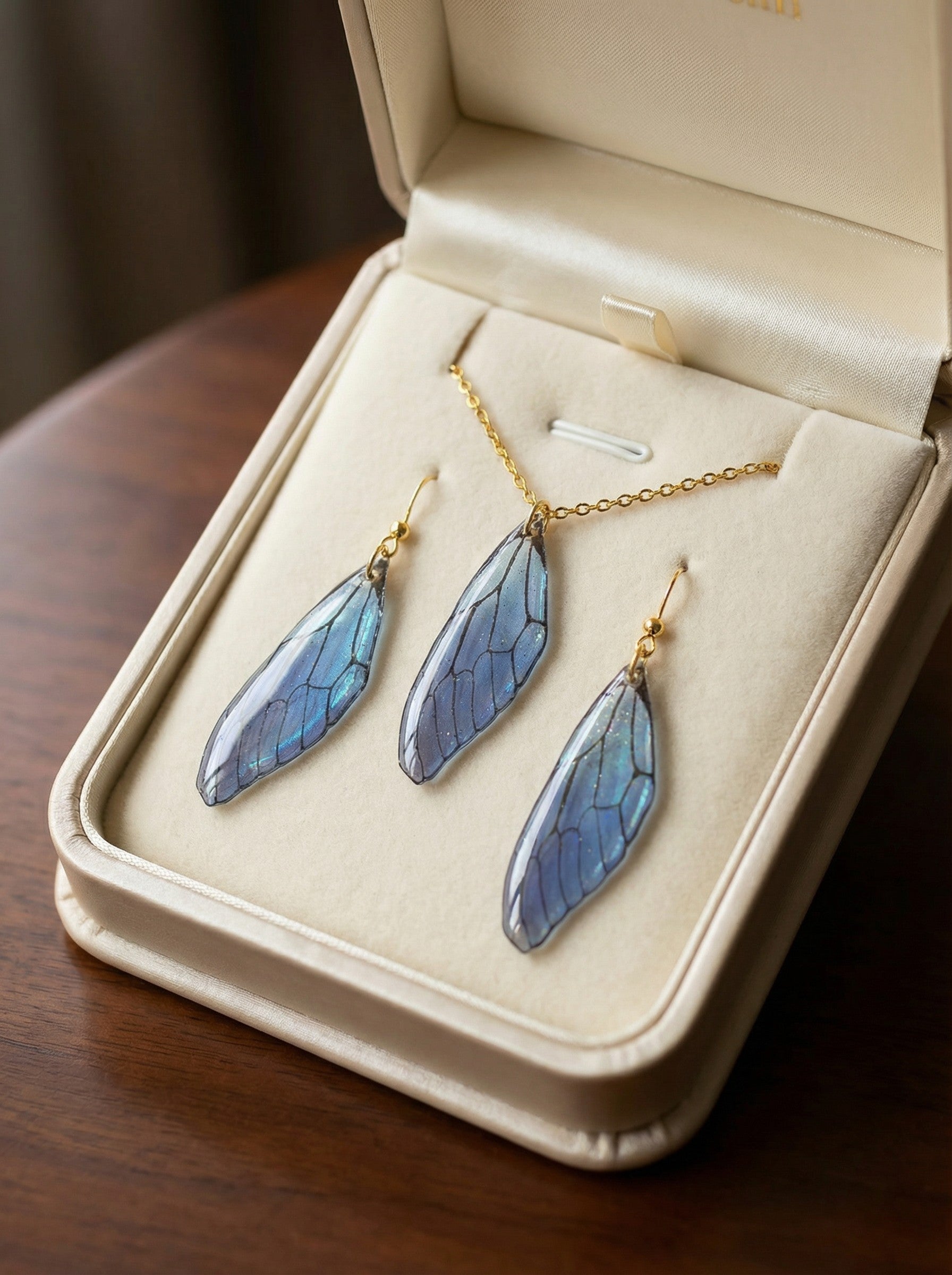 Ensemble collier et paire de boucles d’oreilles - Ailes d’Azur Enchantées, reflet du ciel nocturne, fabriqué en résine bleu irisé avec une monture dorée en acier inoxydable, bijou artisanal unique