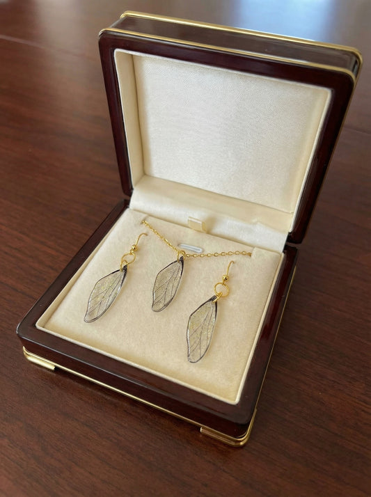Ensemble collier et paire de boucles d’oreilles - Ailes de Fée Cristallines, d'un design artisanal délicat, en résine translucide et acier inoxydable doré, évoquant la magie et la légèreté des contes de fées.