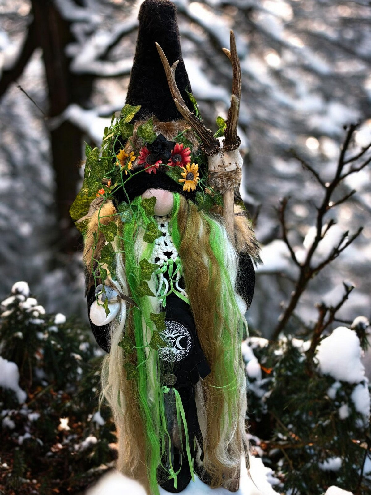 Sculpture artisanale du Gardien de la Forêt Sauvage par Crea Cris 77, représentant un gnome mystique avec cheveux blonds et verts, orné de feuilles de lierre et brandissant un bâton en bois de cerf, apportant une touche magique à votre décoration intérieure ou extérieure.