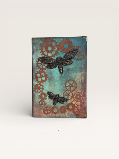 Couverture du carnet Steampunk Papillons, mettant en avant des engrenages patinés et des papillons métalliques, symboles de créativité et de liberté.