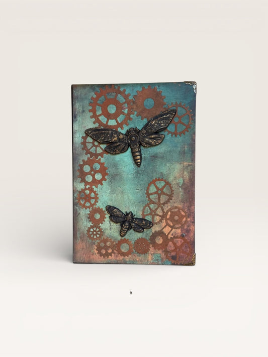 Couverture du carnet Steampunk Papillons, mettant en avant des engrenages patinés et des papillons métalliques, symboles de créativité et de liberté.