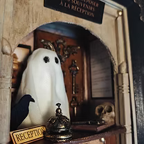 Miniature de L'Hôtel des Brumes, illustrant le comptoir ancien avec une cloche dorée et un registre jauni, transportant les visiteurs dans un monde de souvenirs oubliés.