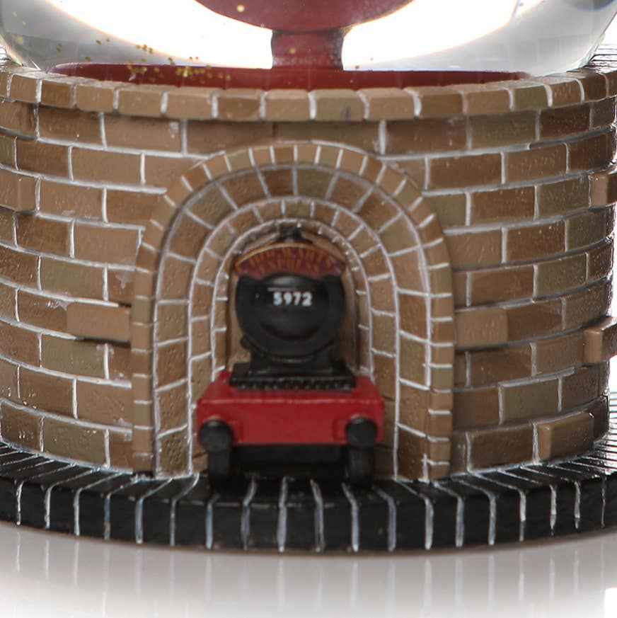 Boule à neige Harry Potter Plateforme 9 3/4 en polyrésine, fabriquée par Half Moon Bay, capturant la magie et l'enchantement de l'univers sorcier.