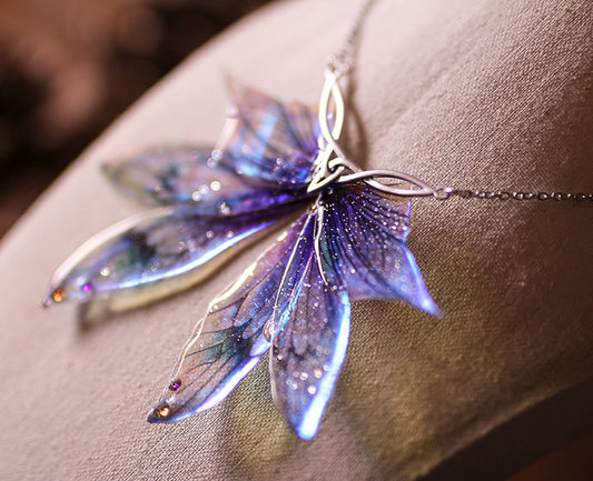 Détails des Ailes de fée holographiques du collier La Larme de l’Aube, révélant des couleurs arc-en-ciel brillantes.