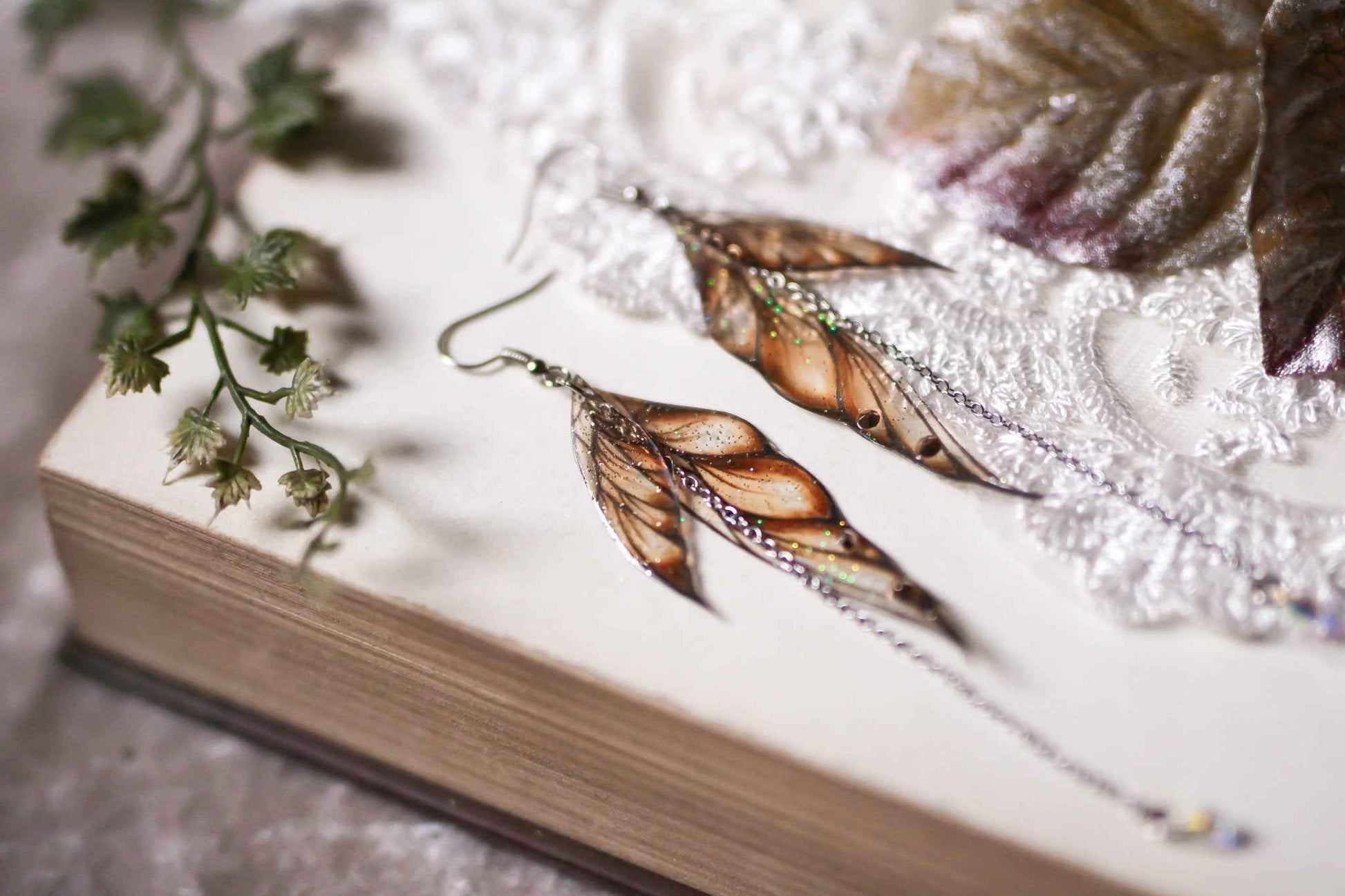 Boucles d'oreilles Conte de Fée par Faërie avec des ailes dorées scintillantes, ornées de paillettes irisées et de strass, parfaites pour illuminer votre style et créer une ambiance magique.