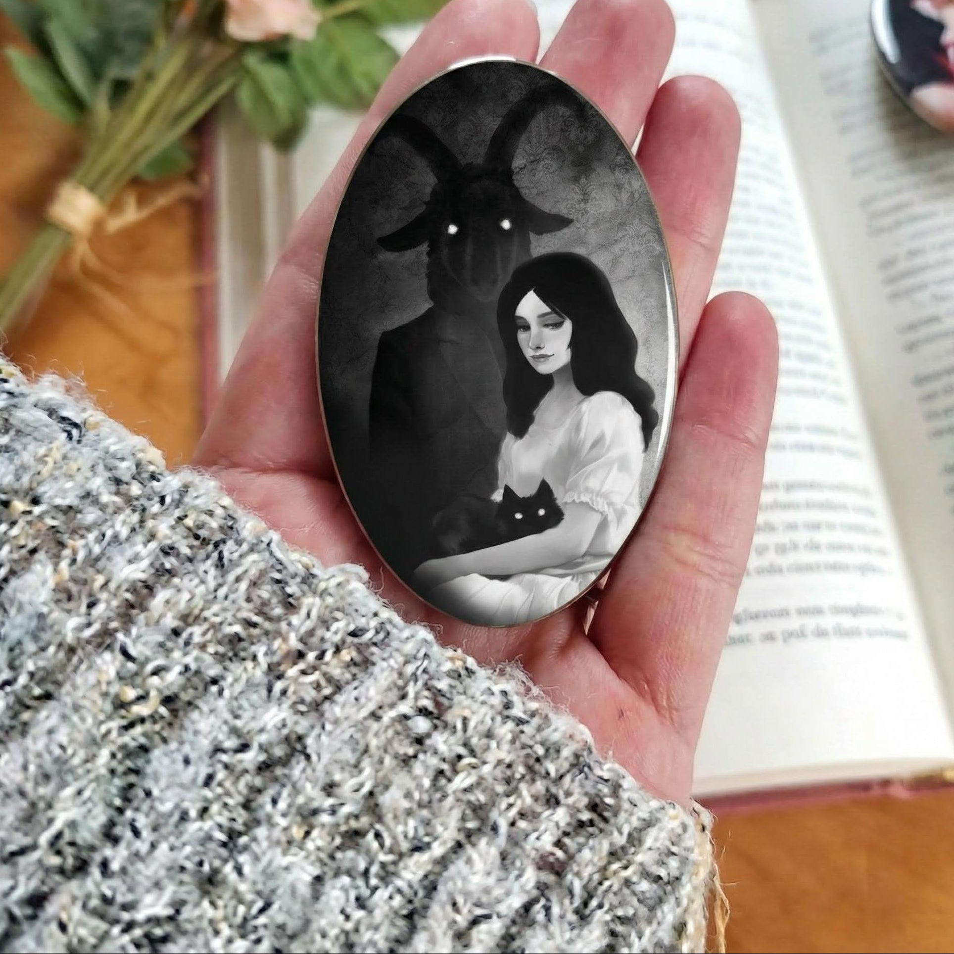 Badge - Portrait de Sorcière : illustration captivante d'une femme en robe blanche tenant un chat noir, avec une silhouette mystérieuse en arrière-plan, alliant douceur et mystère.