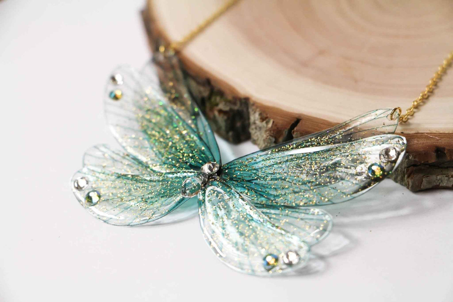 Pendentif Île aux Fées de Faërie, illustrant des Ailes de Fées turquoise ornées de paillettes irisées, ajoutant une touche d'élégance et de magie à chaque look.