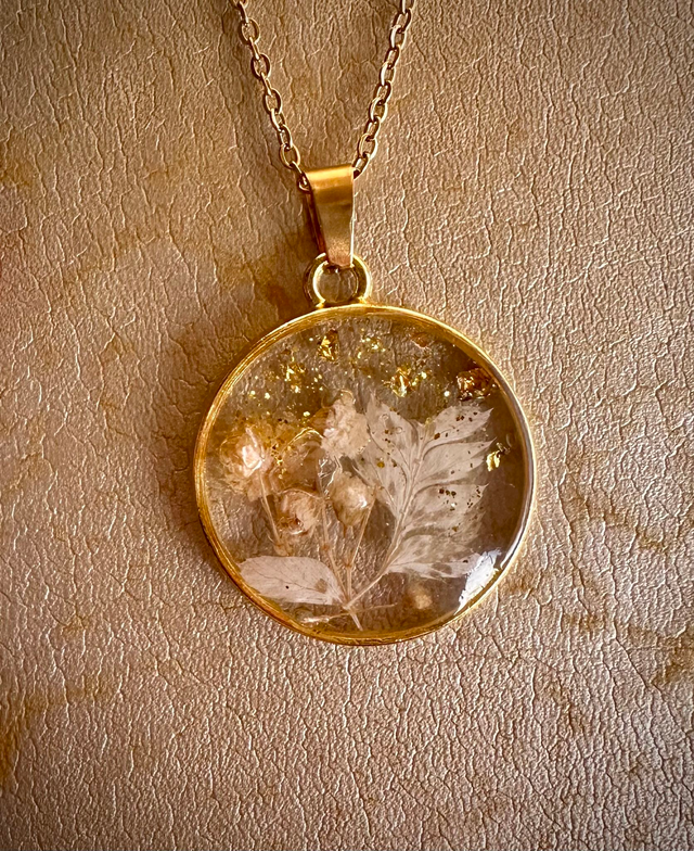 Collier résine fleurs feuilles d’or de Jessica Deelyah, bijou artisanal élégant capturant la beauté des fleurs séchées dans une résine cristalline.