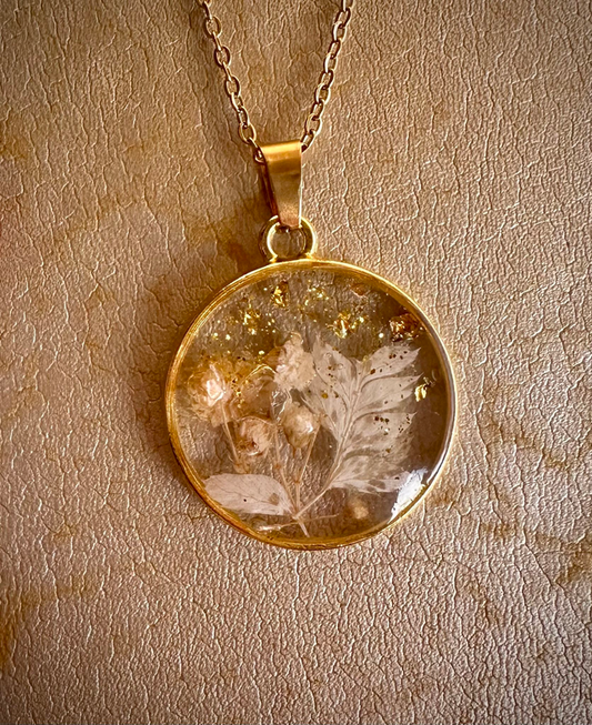 Collier résine fleurs feuilles d’or de Jessica Deelyah, bijou artisanal élégant capturant la beauté des fleurs séchées dans une résine cristalline.