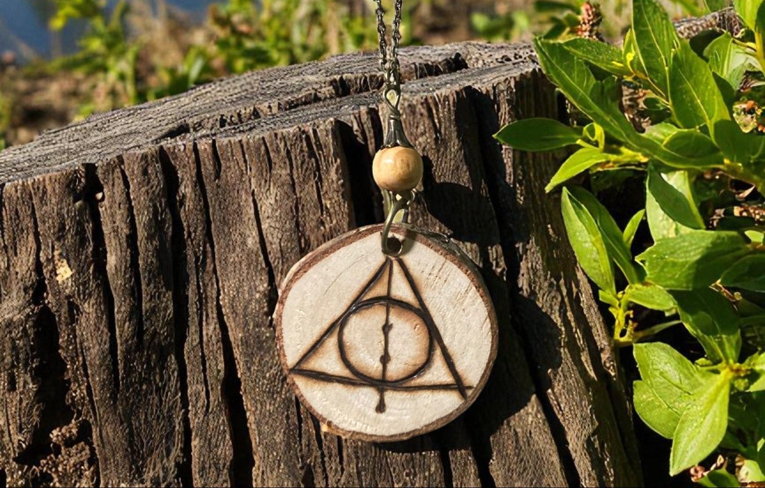 Pendentif Reliques de la Mort de Faërie, un bijou artisanal en bois naturel avec pyrogravure unique, symbolisant la magie et l'artisanat traditionnel.