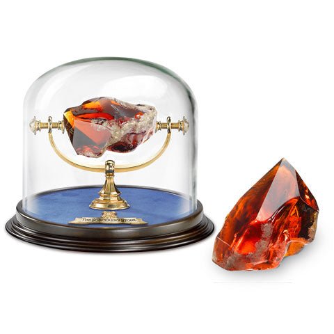Réplique authentique de la Pierre Philosophale de Noble Collection, un artefact légendaire issu de l'univers magique d'Harry Potter, illustrant son éclat en lucite translucide avec un présentoir sous dôme.
