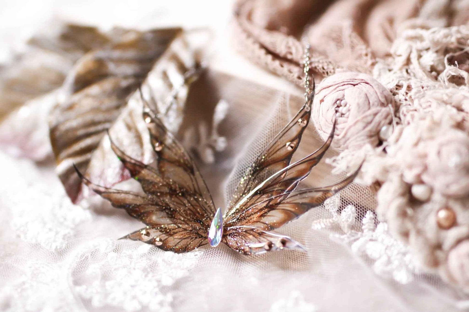 Collier Plume de Griffon de Faërie avec des ailes de fées en dégradé doré, orné de paillettes irisées et strass scintillants, capturant la lumière avec une navette en cristal Swarovski.