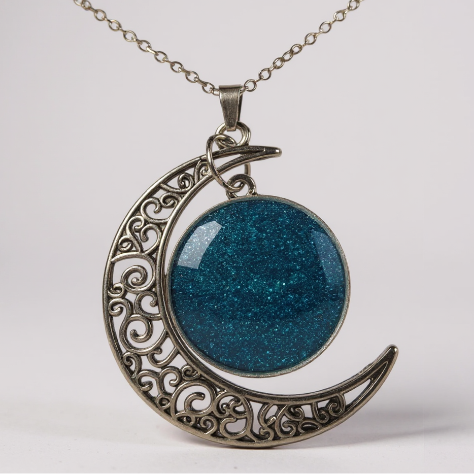 Collier pendentif - Lune en acier inoxydable argenté avec un cabochon scintillant, illustrant l'élégance et le mystère de l'univers.