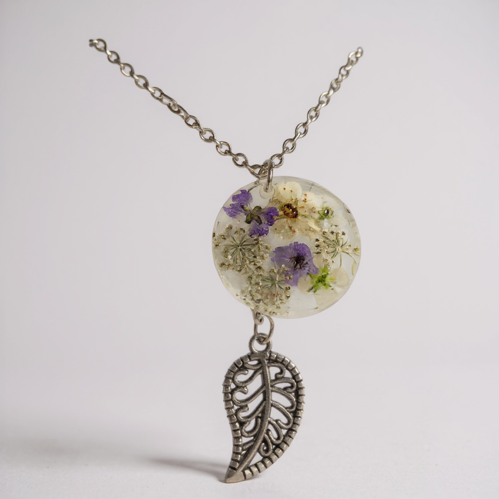 Collier pendentif - Feuille des Jardins Secrets, un bijou artisanal en acier inoxydable avec un médaillon orné de fleurs séchées, qui capture l'élégance de la nature.