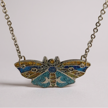 Collier pendentif « Papillon Mystique des Lunes » - un bijou en forme de papillon de nuit, orné de bleu, doré et turquoise, idéal pour une touche d'élégance nocturne.