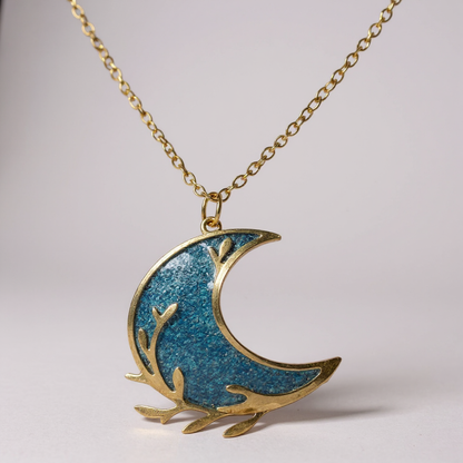 Détail artisanal du collier pendentif - Lune, mettant en avant la finesse du design et la brillance du cabochon dans un cadre fait main.