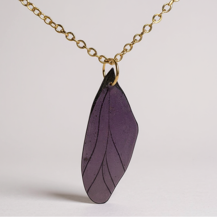 Collier pendentif Aile de fée artisanal, symbole de magie et de délicatesse, fixé sur un fond élégant.