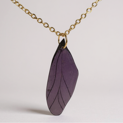 Collier pendentif Aile de fée artisanal, symbole de magie et de délicatesse, fixé sur un fond élégant.