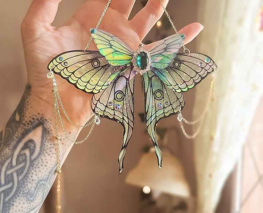 Papillon suspendu Source Emeraude de la marque Faërie, décoratif et lumineux, évoquant des rêves scintillants avec ses ailes translucides et son voile nacré iridescent.